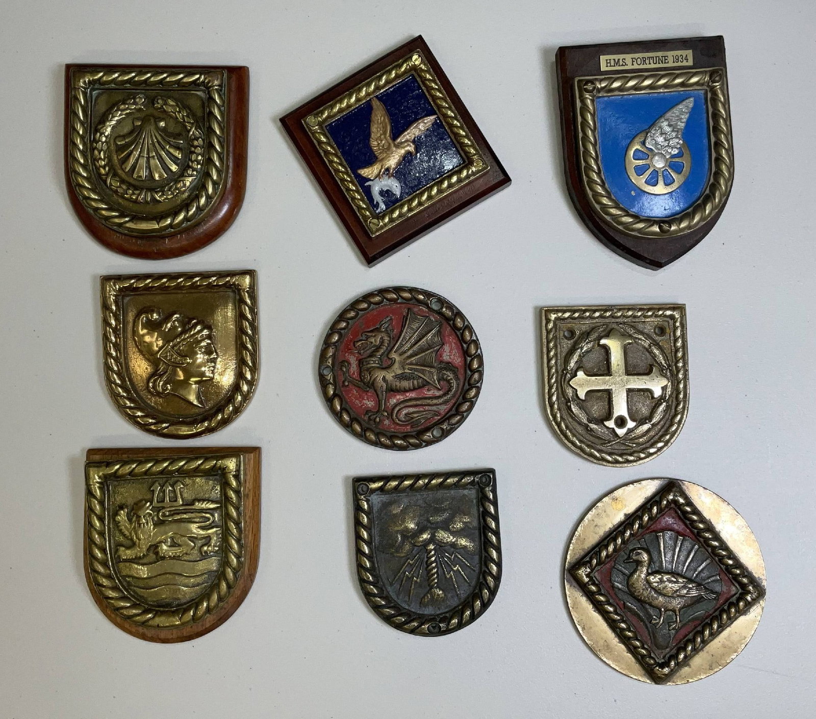 Quality Lot of Nine Chatham Pattern Ships’ Badges: British Royal Navy ships’ badges from notable warships, including HMS Spencer, HMS Osprey, HMS Amazon, HMS Marlborough, HMS Trafalgar, HMS Jersey, HMS Kelvin, and submarine HMS Sheldrake. 28 lbs 9 p