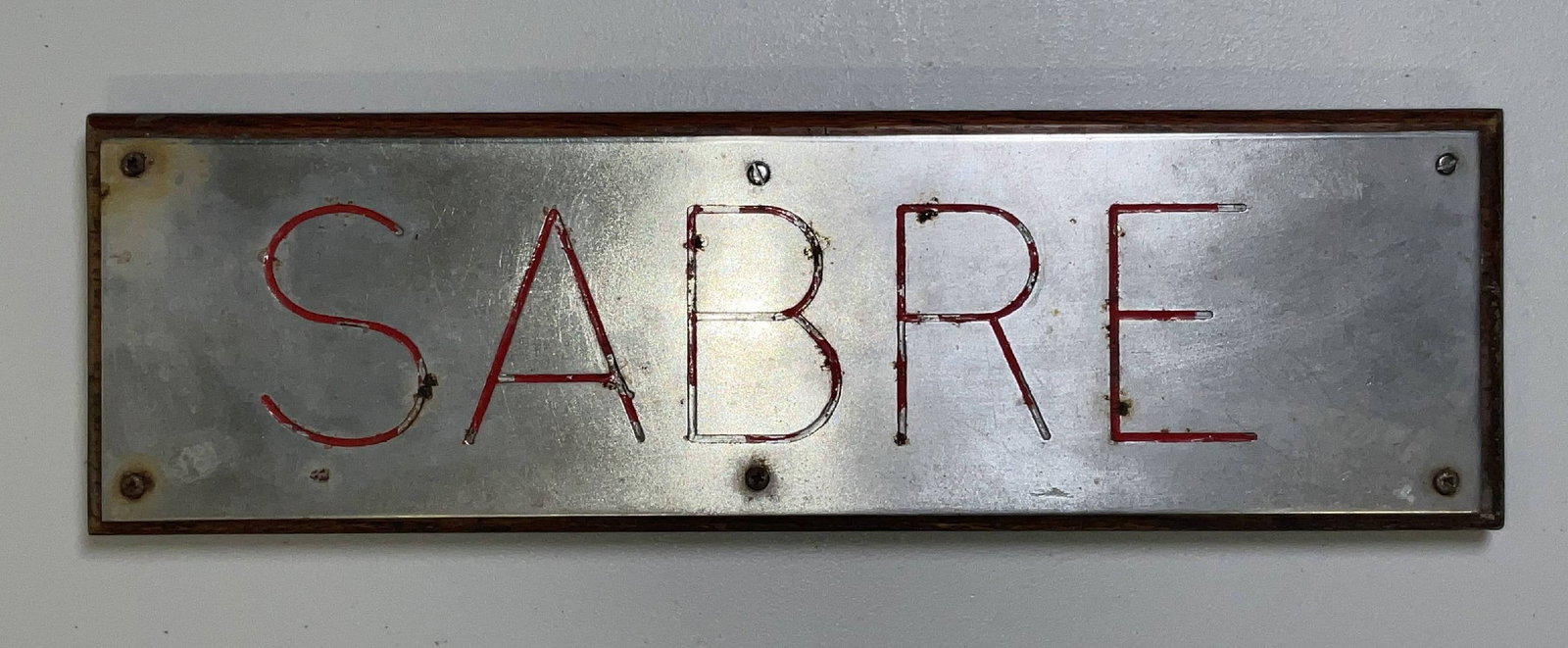Nameboard from Royal Navy Patrol Boat HMS Sabre: Nameboard from the HMS Sabre, a patrol boat built by Vosper in 1970. Metal nameboard is steel with red painted letters. 7 lbs. 6"H x 19"W.
