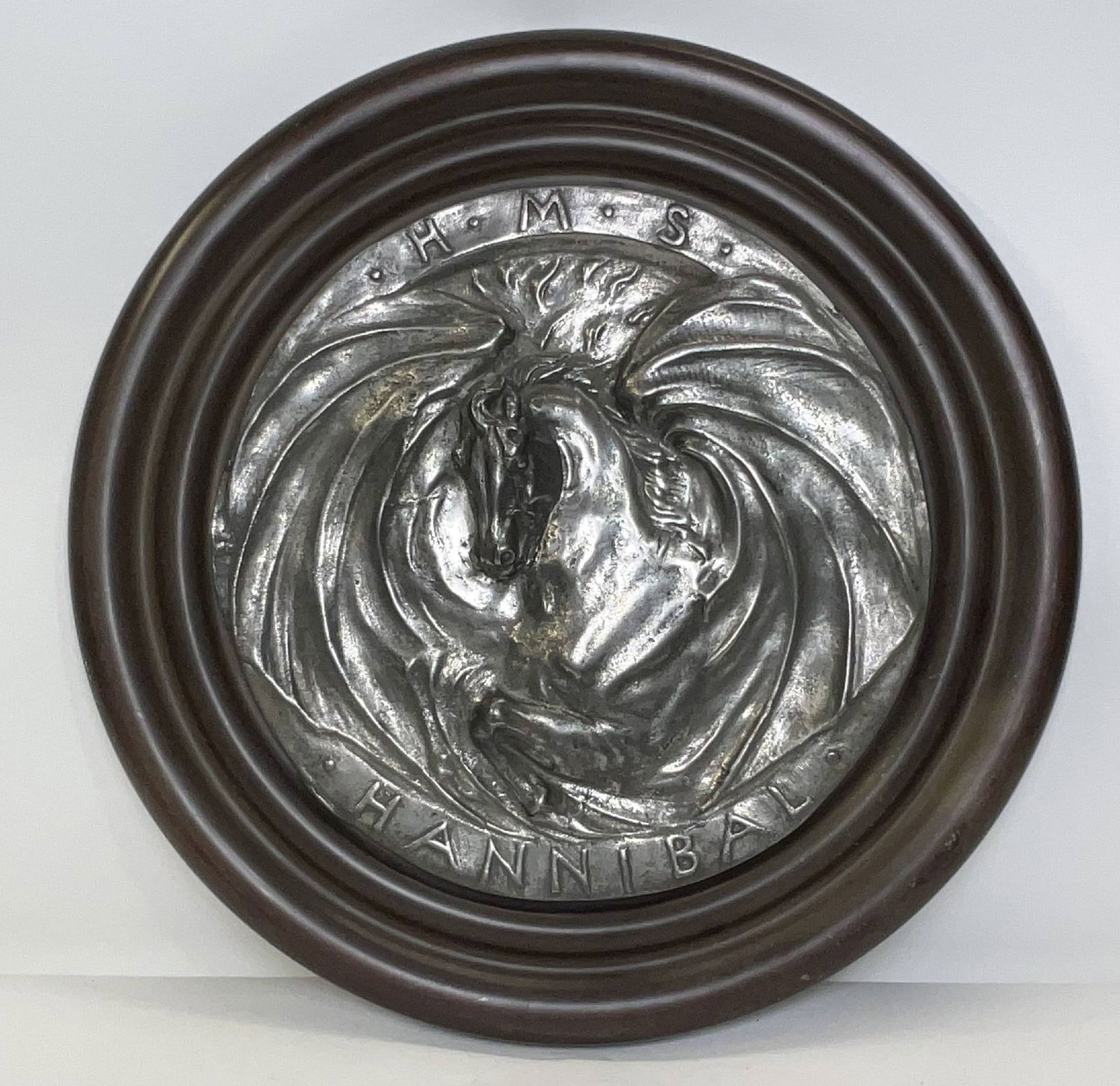 Gun Tompion from the Royal Navy Warship HMS Hannibal: Cast steel tompion from the Majestic-class battleship HMS Hannibal from 1896. Very artistic piece mounted to a wood backboard. 9 lbs. 17" Diameter.