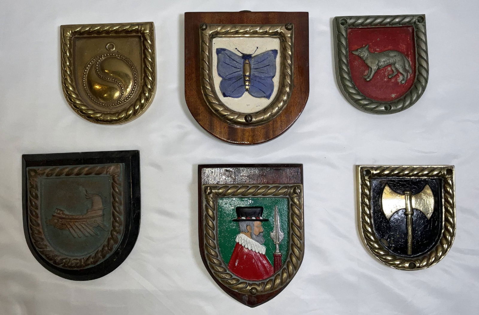Six British Royal Navy Chatham Pattern Ship's Badges: British Royal Navy ship's badges of Chatham Dockyard spec. These are HMS Sardonyx, HMS Vanessa, HMS Jackal, HMS Woolston, HMS Escort, and HMS Tenedos. Rare group. 6 badges. 17 lbs. 7"H x 7"W large.