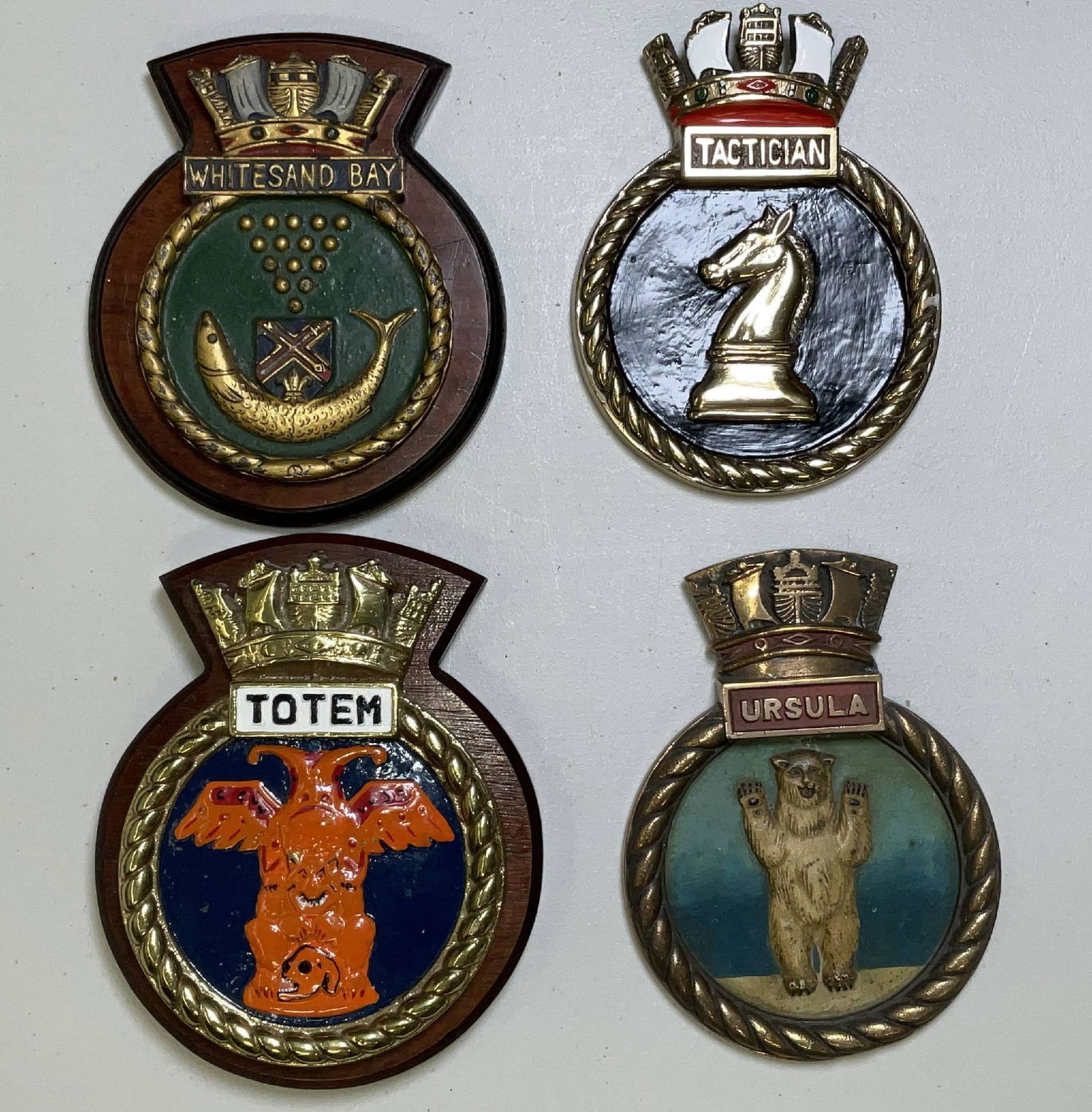 British Royal Navy Ships Badges from Naval Warships: Ships badges from HMS Whiteshand bay, HMS Tactician, HMS Totem, and HMS Ursula. All are circular with rope border and Royal Navy crowns at top. 21 lbs 4pcs. 10"H x 8"W big. 9"H x 7"W small.