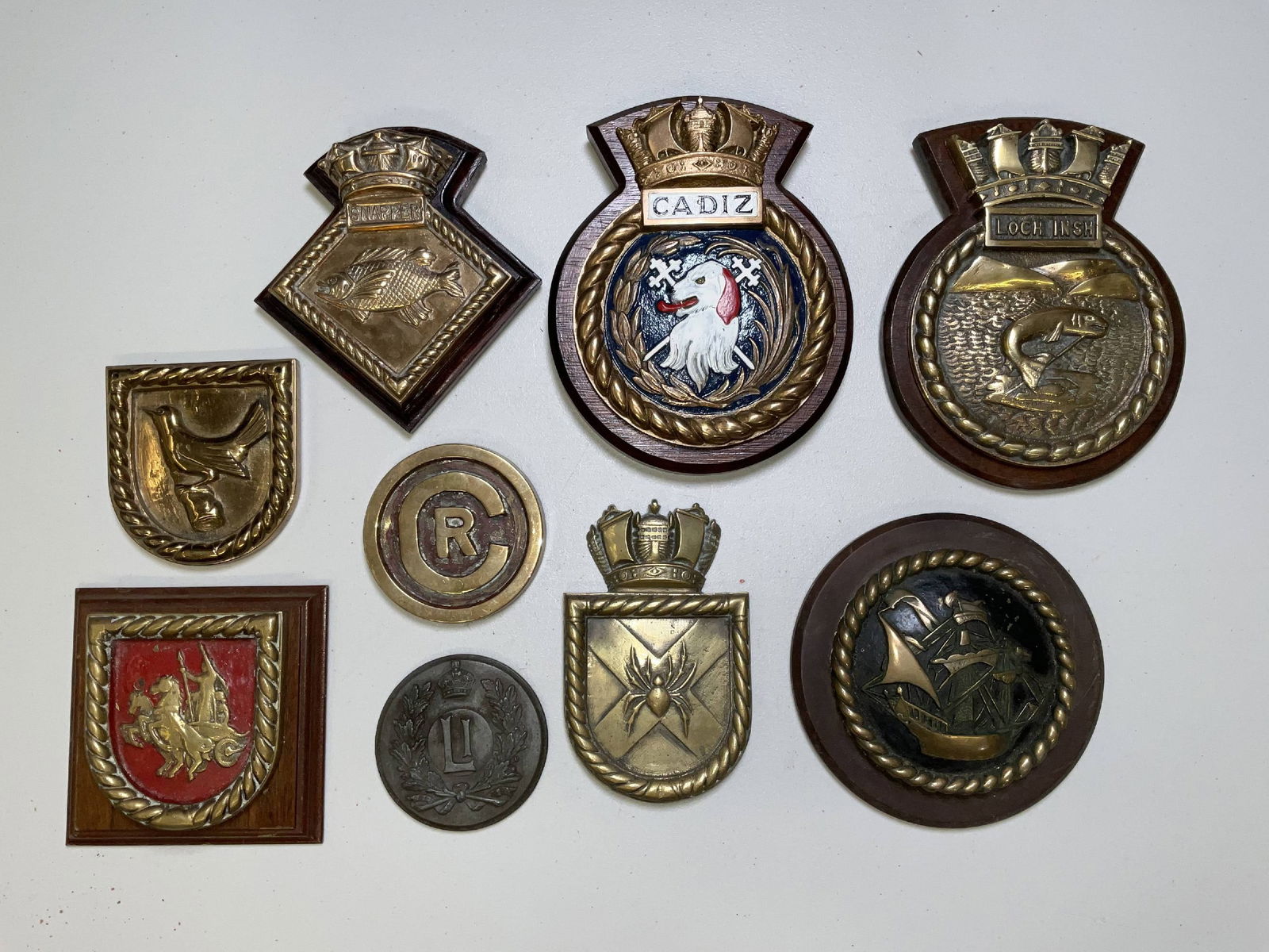 British Royal Navy Gun Tompions and Badges from HMS Warships: Nice group of Royal Navy items, including some Chatham Dockyard badges and tompions, and HMS Wren, HMS Bruce, HMS Boadicea, HMS Loch Insh, HMS Snapper, HMS Cadiz, and others. 37 lbs, 9 pcs. 10"H x 8"W