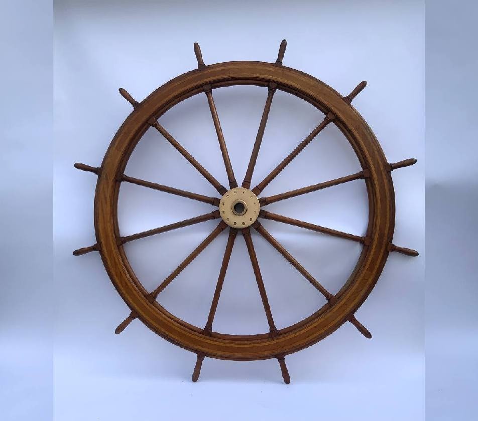 Seven Foot Ships Wheel with Brass Hub: Twelve spoke ships wheel with brass hub and satinwood inlay. Varnished finish. Tapered spindles. As big as they come. Circa 1890. American made. Heavy brass hub with polished finish. 220lbs. 84" Diame