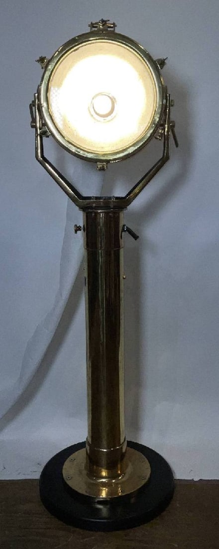 Brass Searchlight: Ship's searchlight with highly polished brass case. Rewired for 110. Mounted to a sturdy swivel yoke that once was a U.S. Navy pelorus stand. The stand is bolted to a mahogany base. 67"H x 20"W x 15"D