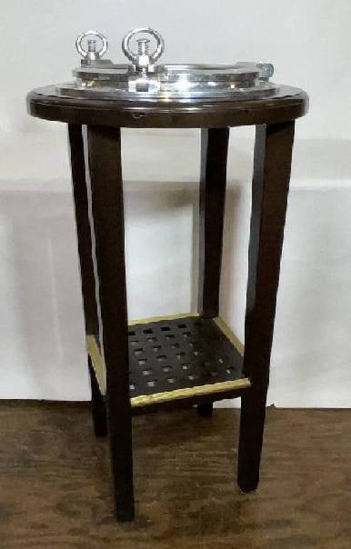 Aluminum Ship's Porthole Table: Aluminum ship's porthole mounted to a tall mahogany table that is bar height, suitable for two barstools. A wood table has a simulated ship's grating for a lower shelf. D: 25" x 41 H".
