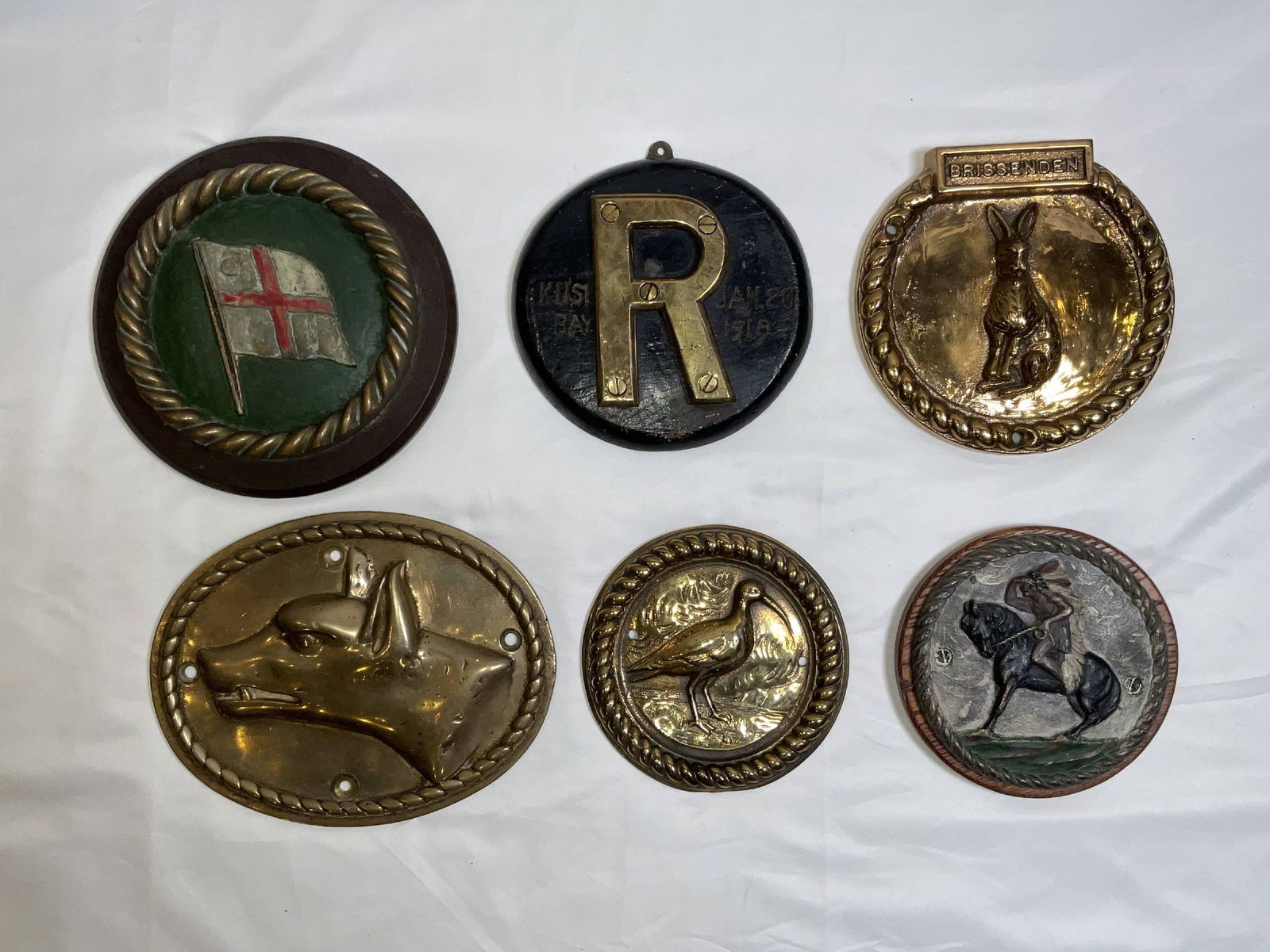 British Royal Navy Ship's Badges and Plaques: Solid brass badges from a Royal Navy Vice Admiral’s badge, HMS Raglan, HMS Brissenden, HMS Wolfhound, HMS Curlew, and HMS Attabaskan. Nice lot. 6 pcs. 22 lbs. 8"Diameter big. 6"Diameter small.