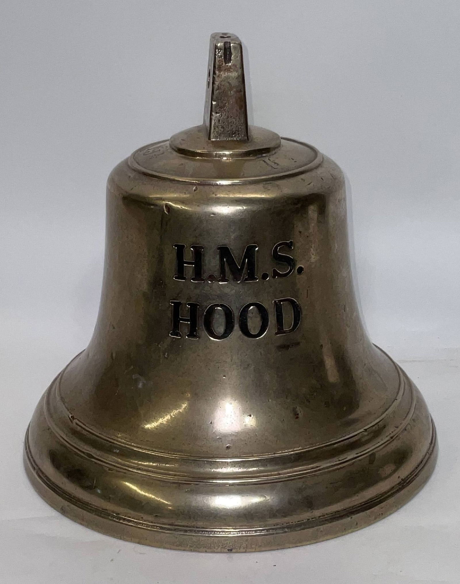 HMS Hood Ship’s Bell from the Royal Navy: Rare British Royal Navy ship’s bell engraved “HMS Hood.” “19 1/2” is engraved on top. Flange mount. This bell would have been from a small craft on the vessel. 20 lbs. 10" H x 10" di