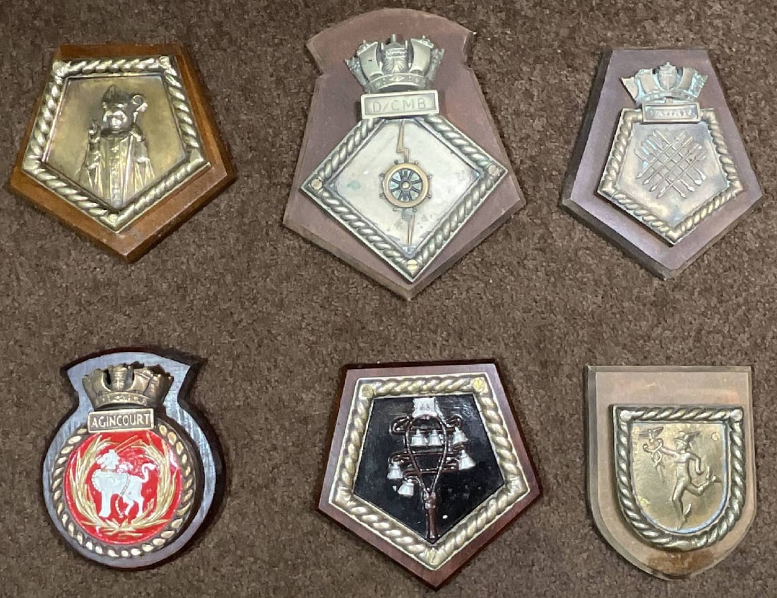 6 Pieces Badges D/CMB/ Sheffield, Agincourt: Group of 6 high-quality Chatham pattern Royal Navy ship’s plaques and badges, which include HMS Agincourt and other finely detailed ship tampions and crests mounted on wooden backboards. Each piece