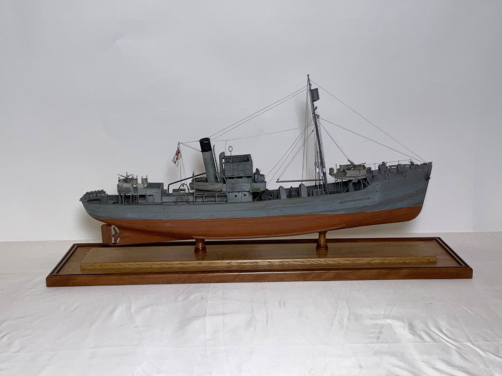 Cased Model of an Armed Trawler of the Royal Navy: Circa 1940 ship model of an Armed Trawler in weathered paint. Highly detailed with all gear, armament, liferafts, davits, etc.. Glass case included. 17"H x 31"W x 9"D. 12 lbs.