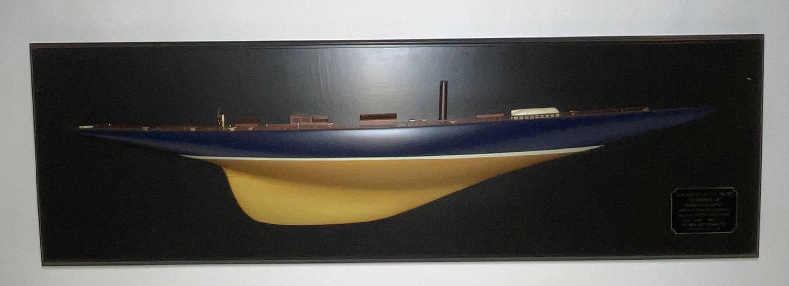 Museum Quality Half Model of Endeavour: 1934 Americas Cup Defender Endeavour half model. Planked mahogany deck with brass winches, skylights, stubbed mast, toerails, etc, on backboard with legend plate. 28 lbs. 17"H x 55"W.