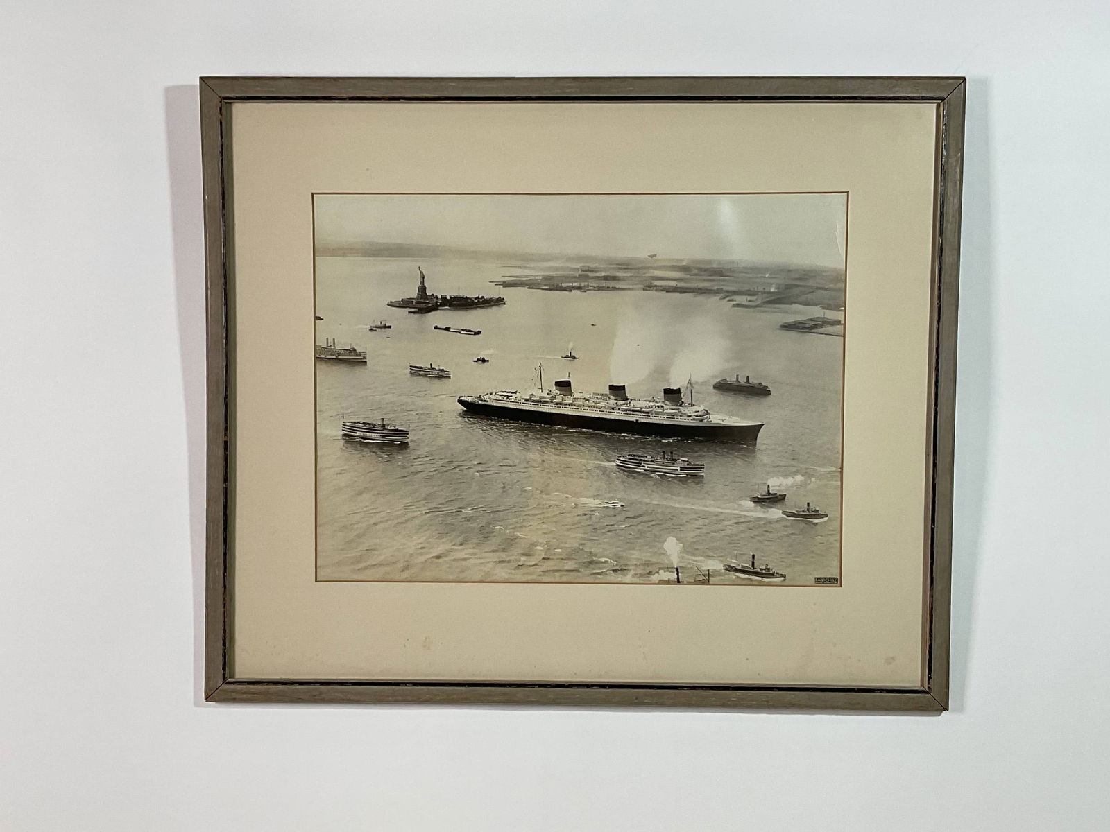 USS Normandie Arriving in New York Harbor on Maiden Voyage: Photographic print by Fairchild Aerial Surveys Inc. This is a famous aerial view with the Statue of Liberty in the background, a Staten Island Ferry, and other steamships. 5 lbs. 21" H x 25" W.