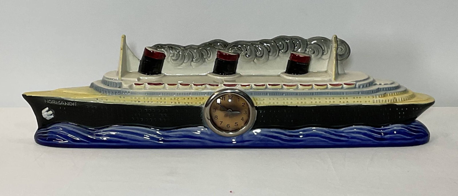 Porcelain Ocean Liner Normandie Clock Collectible: Ceramic model ship Normandie with French made clock. Colorful collectible. Wind up clockworks. 18 lbs. 7"Diameter.