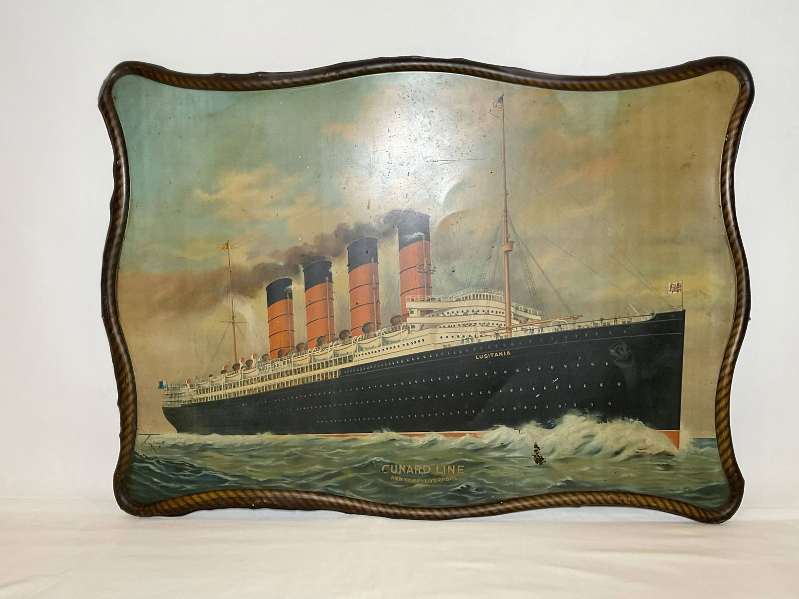 Cunard Line Promotional Piece for Ocean Liner Lusitania: Chromolithograph of the four stack ocean liner Lusitiania on metal with a simulated rope frame. "Cunvard line, New York" to liverpool is printed lower center. With marks and scratches provenance: Ex