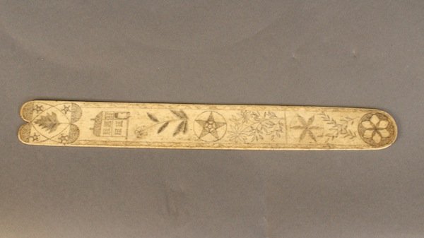 19th century scrimshaw: Whalebone Busk, Sailor-Made Scrimshaw, mid-19th Century, engraved with hearts, compass rose, florals, stars and house, heart-shape cutout at top. 14 inch length.