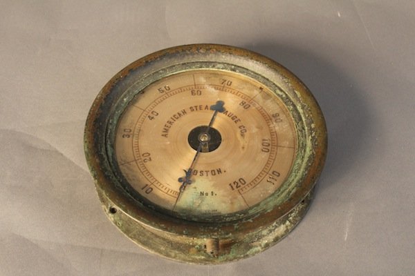 Brass gauge by American Gauge, Co.,: Brass caed steam gauge with engraved faceplate. “American Steam Gague Co., Boston, No. 1” with increments to 120s. Also engraved D. Lane steam gauge and serial number 169780