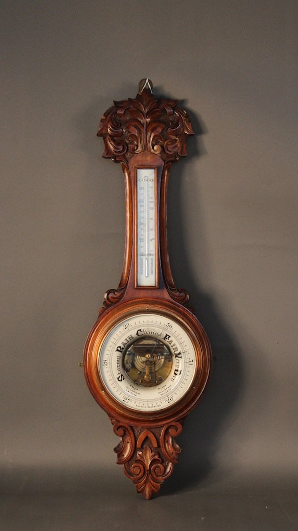 Walnut barometer with porcelain faces.: Antique walnut barometer with bellows and mercury thermometer. Deeply carved design. copper bezel and beveled glass on barometer. 11” diameter x 34” tall.
