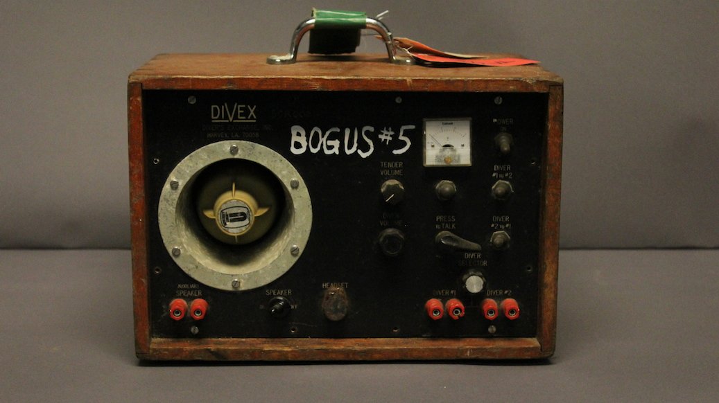 Diver's Hard Hat Diving Radio: Divex brand hard hat diver's communication radio. A two diver model with built in speaker, control buttons, levers, toggles etc. Mounted into a timber box.