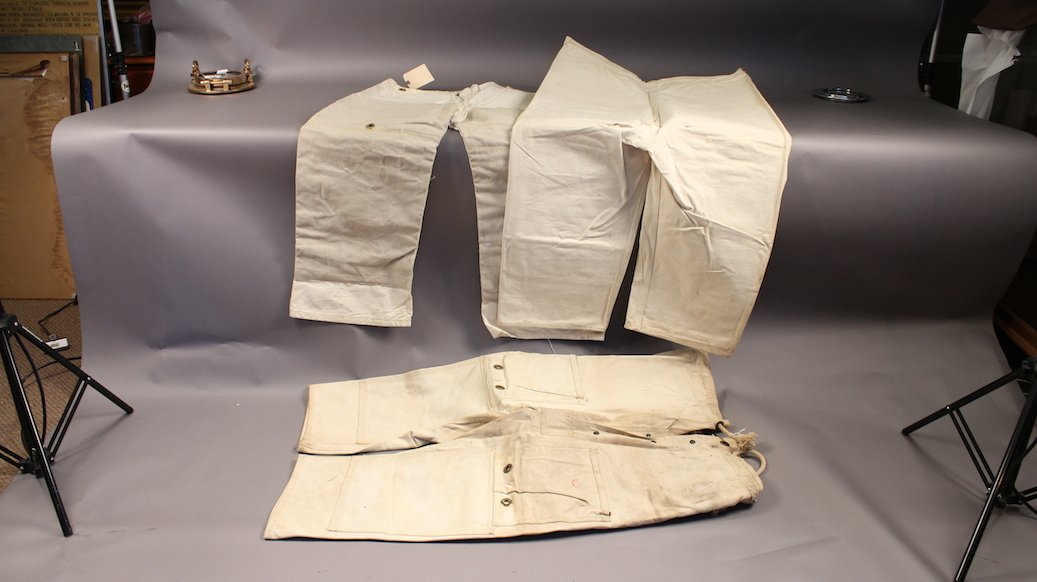 Hard Hat Diver's Chafing Pants: Three pair of deep sea diver's 'chafing pants'. Heavy canvas with brass grommets. Two are by a PIttsburgh maker. Maker's name is indistinguishable.