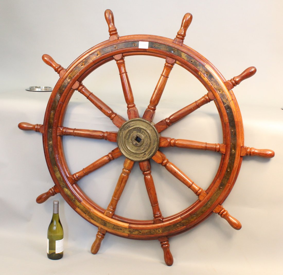 Eight spoke ship’s wheel: Heavy teak ship’s wheel with eight turned spokes, solid brass hub and inlaid brass trim ring. 50” diameter.