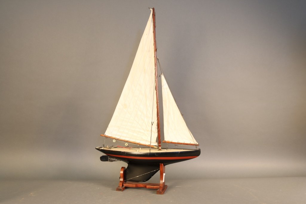 Bassett Lowke Pond Yacht "Heather Dew": Bassett Lowke pond yacht "Heather Dew" with lead keel. Hull painted black with red waterline. Suit of sails, wood cradle. Overall Dimensions: 22" x 6" x 38" H