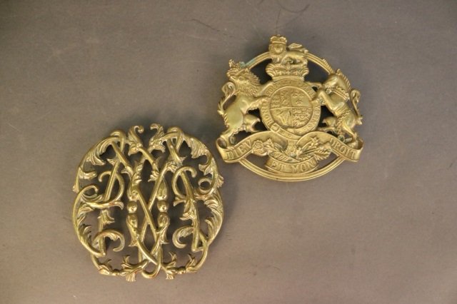Two Antique Brass Trivets: Lot of brass trivets. One with a floral design, one with a crest and a Latin phrase. Overall Dimensions: 5.5" diameter Weight: 8lbs