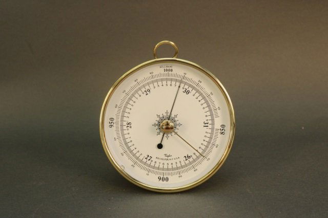 Brass Case Aneroid Barometer: Aneroid barometer by Taylor. Brass case with hanging loop. Dimensions: 5.25" diameter Weight: 3lbs *This lot is part of a maritime antique auction of ship models, nautical relics, marine paintings, bo