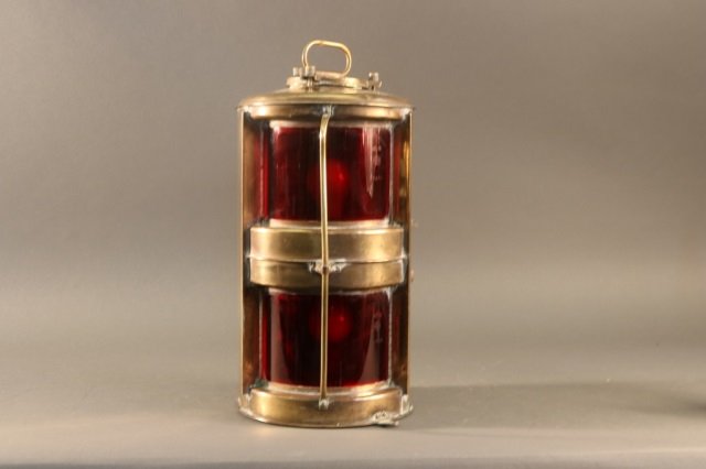 Polished Brass Port Lantern: Highly polished brass lantern with ruby red lenses, carry handle, protective bar, and etc. Dimensions: 9" L x 8" W x 16" H Weight: 8lbs *This lot is part of a maritime antique auction of ship models,