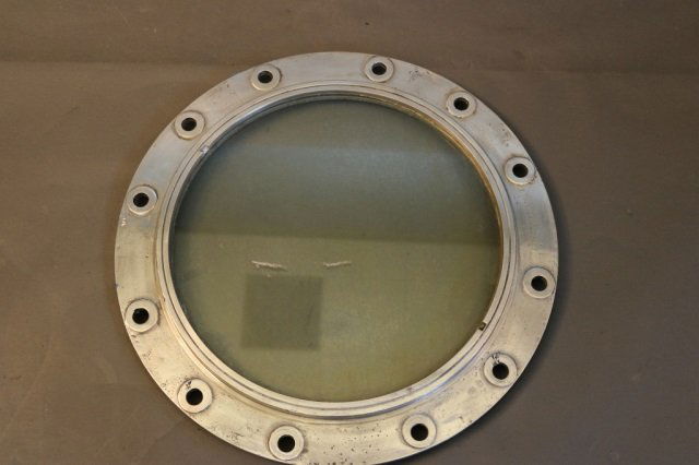 Aluminum Ship's Porthole: Ship's portlight of solid aluminum. Pierced with twelve mounting holes and glass window. Dimensions: 22" diameter Weight: 15lbs *This lot is part of a maritime antique auction of ship models, nautical