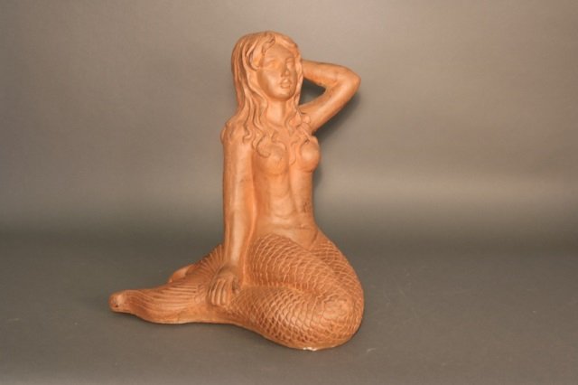 Terracotta Mermaid Sculpture: Terracotta mermaid sculpture with arm behind her head and flowing tail. Dimensions: 17" L x 19" H Weight: 3.5lbs *This lot is part of a maritime antique auction of ship models, nautical relics, marine
