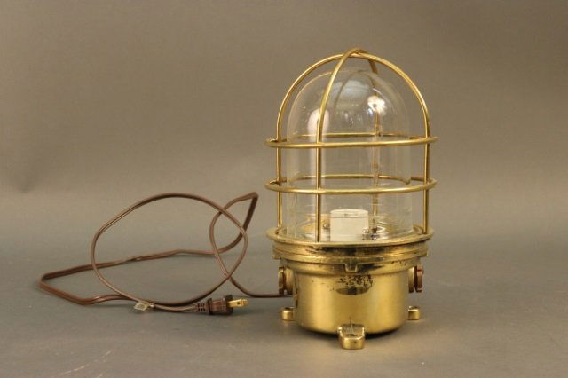 Solid Brass Ship's Bulkhead Light: Brass ship's bulkhead lantern with protective cage, glass lens, electrified. Dimensions: 7" diam. x 11" H Weight: 9lbs *This lot is part of a maritime antique auction of ship models, nautical relics,