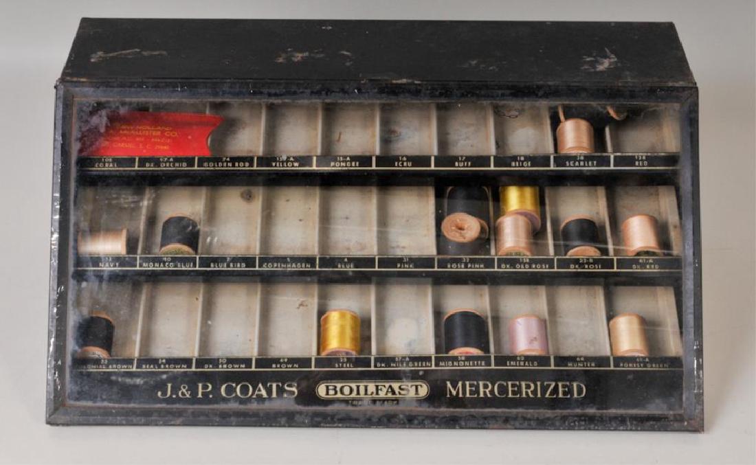 J. & P. Coats Boilfast Spool Cabinet: Counter display spool cabinet, slant front glass lid on hinge lifts to interior with three divided shelves for holding spools of thread, black painted metal with thread numbers and colors on each shel