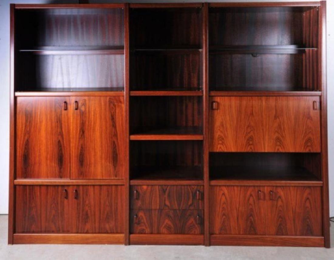 Danish Mid-Century Modern Rosewood Wall Unit: Three-section Danish rosewood wall unit, top of each section with glass shelves and diffused lighting behind glass doors; third section with drop down mirrored door opening to a dry bar with mirrored 