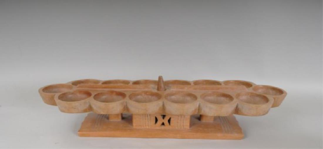 Wooden Mancala or Oware Game Board: West African, carved mahogany, seed pods stored in central receptacle; 23" x 7 1/4", 5 1/4"H---From the collection of a South Carolina gentleman who purchased this in 1969-70 while living in Africa. (