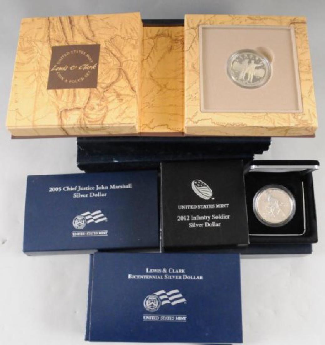 7 United States Mint Commemorative Silver Dollars: Lewis & Clark Bicentennial Silver Dollar (x2), 2005 Chief Justice John Marshall Silver Dollar, 2012 Infantry Soldier Silver Dollar (x2), Lewis & Clark Coin & Puch Set (x2). ref: 32, 33, 34,35