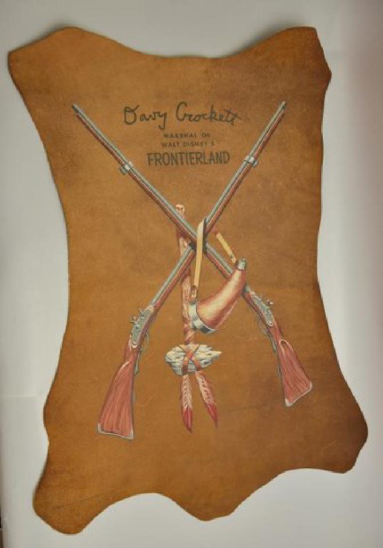 Walt Disney Davy Crockett Leather Display Sign: c. 1955, painted leather sign advertising "Davy Crockett Marshall of Walt Disney's Frontierland" over a depiction of two rifles, a tomahawk and a powder horn; stamped on reverse "For Use Only With The