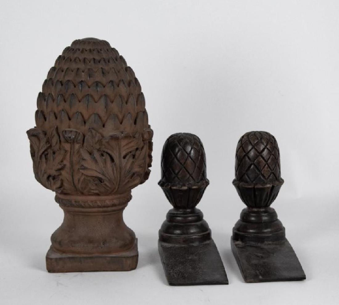 Carved Wood Pineapple Doorstops, Pineapple Finial: Two carved wood doorstops in the form of pineapples; 7 1/2"L x 3"W, 6 5/8"H---Large faux wood finial in the form of a pineapple; 11 3/4"H, 6 1/4W