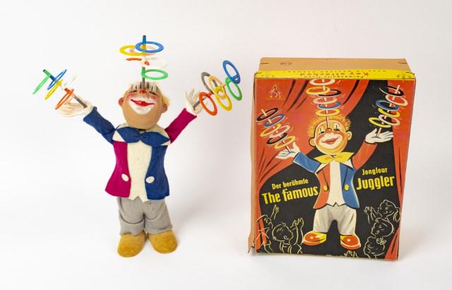 Wind-Up Toy--The Famous Juggler w/ Original Box: Made in Western Germany by Hans Zitzmann, juggler clown with painted features and dressed in multi-colored felt outfit balances three multi-tiered plastic hoops on hands and forehead; 10 1/2"H; in wor