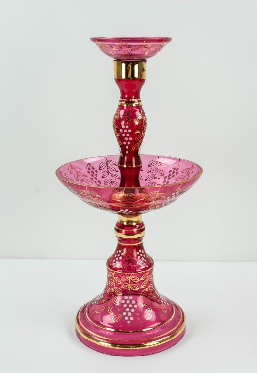 Cranberry Glass Epergne w/ Enamel Decoration: Cranberry glass epergne decorated with white enamel grape custers, gilt leaves and gilt accents, 20th century; 19"H, 9" dia.; minor chip to outer rim of center bowl