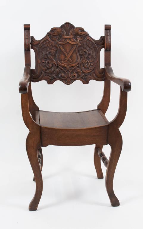 Highly Carved Walnut Curule Chair: Shaped backrest centering a double-headed eagle with shield and clutching crossed swords in talons, flanked by carved and scrolled ears, down-scrolling arms terminating in scrolled handholds, slightly