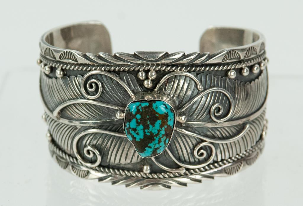 Native American Ornate Sterling Cuff Bracelet: Probably Navajo; ornately decorated with feather, scroll and beaded designs; turquoise center stone; marked "Sterling"; 1 3/4"W, wrist circumference approx. 6", gap 1 1/16"