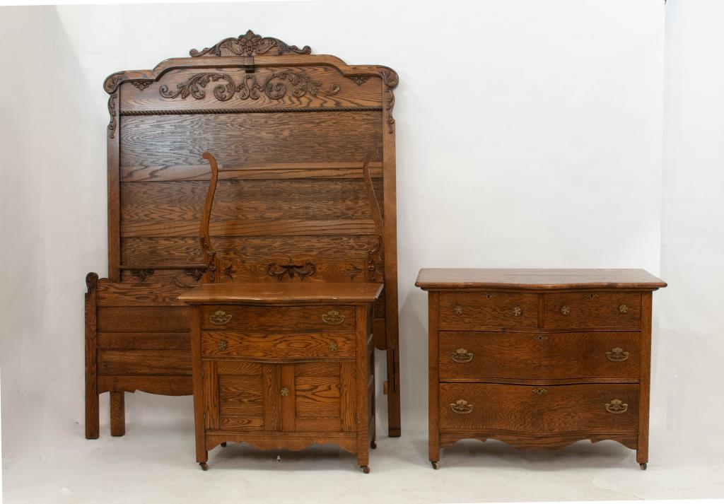 Early 20th C. Three-Piece Oak Bedroom Set: Includes bed with headboard, footboard and side rails, washstand and chest of drawers: Headboard and footboard with applied carvings, shaped side rails; 58 1/2"W, 80"H, 76 3/4"L; Washstand with shaped
