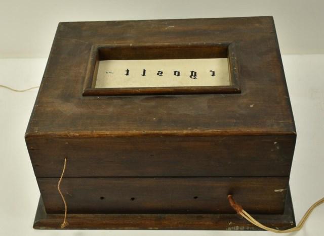 Early Optometrist Lighted Eye Testing Box: Early 20th century, wooden box with hinged lid having a rectangular opening on top, interior with paper eye chart for vision and color blindness tests mounted on two rollers with light and reflecting