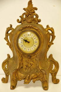 Gilt Iron Mantle Clock: Scroll decoration with two putti at lower center; face marked "Mercedes" and "Made in Germany"; Roman numerals; 11 1/4"H, 7 3/4"W