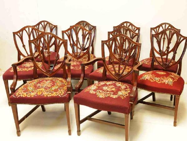 Ten Hepplewhite Style Shield-Back Dining Chairs: Consisting of two armchairs and eight side chairs; shield-back with a wheat motif; reeded legs with spade foot; petit point and needlepoint seats (all worked by a gentleman who was the heir to the Uni