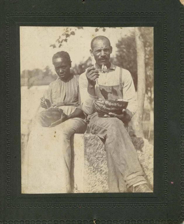 Black Memorabilia--Three Vintage Photographs: Including: 1. Vintage photograph of a black man and woman sitting and eating watermelon; photo 2 3/4"W, 4 3/4"H; mounted on black card 5 1/2"W, 6 1/2"H with embossed border designs; wear and slight lo