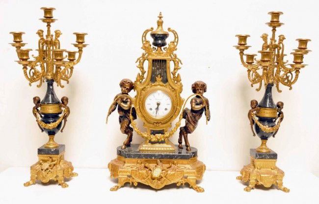 Italian Brass & Marble Clock Garniture Set: In the Louis XVI style; clock with white enamel dial and Roman numerals, marked "Imperial" and flanked by classical figures; eight-day balance-wheel time-only movement, 24"H, 13 1/2"W, 8 1/2"D; and a