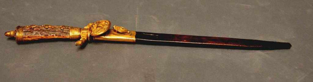 Gilt Mounted German Short Hunting Sword: Stag grip with three applied brass acorns and an acorn pommel; gilt S-type crossguard formed by a dog's head each side with hoof protruding from his mouth; gilt clamshell guard having dog with