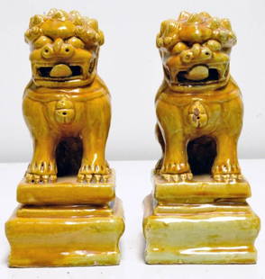 Pr. of Chinese Yellow Glazed Ceramic Foo Dogs: Mustard color; each seated on a rectangular plinth; probably early 20th century; 8 1/2"H, 4 3/4" x 4"; firing flaw to front of one