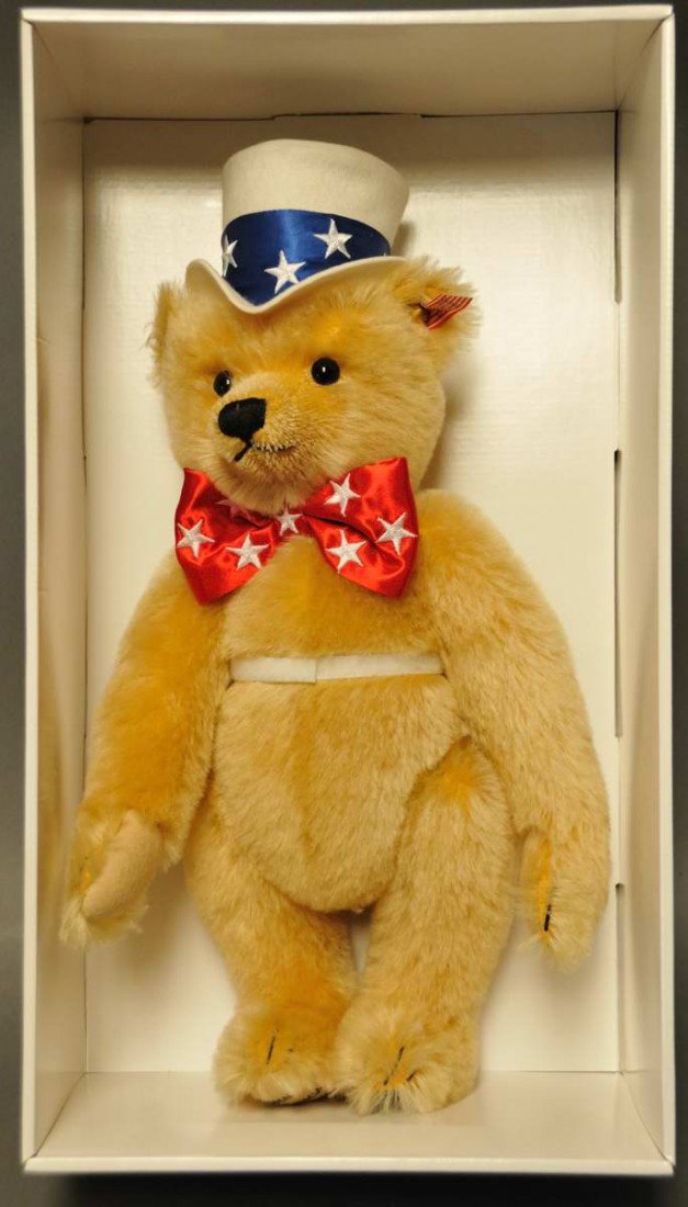 Steiff "First American Teddy": Wearing an Uncle Sam top hat and red bow tie with white stars; customized ear tag of miniature American flag; blond mohair; original box; 15"; c. 2003