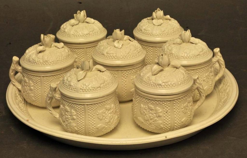 Italian Creamware Pots-de-Creme Service: Eight-piece Italian creamware pots-de-creme service in the 19th century style; circular tray, 11" diameter, and seven covered pots-de-creme, all with bas-relief foliage decoration, domed lids with clo